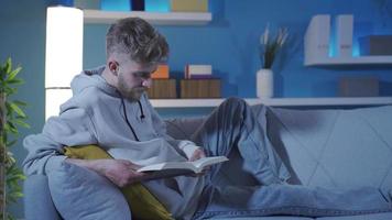 das Mann ist lesen ein Buch auf das Sofa. wendet sich das Seiten von das Handbuch, das Mann Träume, er Likes zu lesen. faszinierend Buch. video