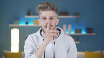 Portrait of young man warning and gently shh gesture leaf silence and admonishment. Young man making a shush gesture while looking at the camera warns. video