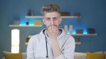 Young man biting his nails is worried and needs to think in a panic. Young man biting his nails looking worried and panicked in front of the camera at home. video