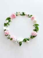 Round frame of pink and white carnations, leaves photo