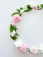 Round frame of pink and white carnations, leaves photo