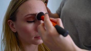 Maquiagem artista aplica-se pó e faz a correção do a face forma para a menina video