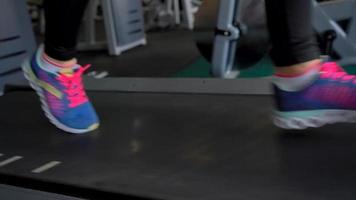 Woman running on treadmill in gym, slow motion video