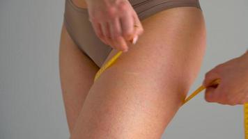 Woman measures her leg with measuring tape video