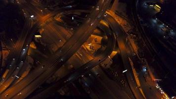 Vertical top down aerial view of traffic on freeway interchange at night, quickly speed video