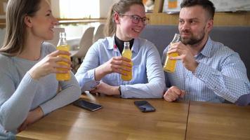 Trois copains asseoir dans une café, boisson jus et avoir amusement communicant video