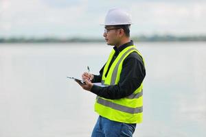 Environmental engineers work at water source to check for contaminants  in water sources and analysing water test results for reuse.World environment day concept. photo