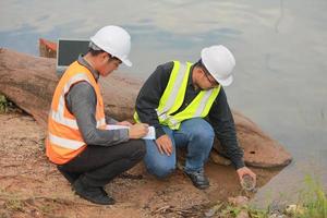 Environmental engineers work at water source to check for contaminants  in water sources and analysing water test results for reuse.World environment day concept. photo