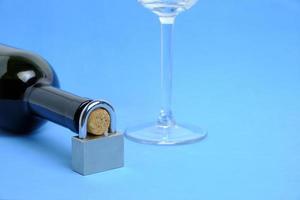 vaso y botella de vino con candado en el cuello sobre fondo azul.concepto prohibición de beber, prohibición. foto