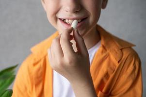 niño en naranja camisa sonriente y planes a comer un grande vitamina foto