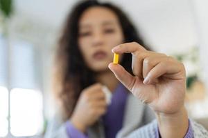 Coronavirus and healthcare concept. Selective focus on pill in hands of asian woman at blurred background. Retirement lady take medicine at home photo