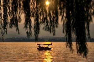 beautiful hangzhou in sunset, ancient pavilion silhouette on the west lake,China - Boat Focus photo