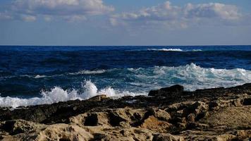 Blue sea wave and white foam and splash. Stone beach on island of Malta, no sandy beach. Summer holiday border frame concept. Tropical island vacation backdrop. Tourist travel banner design template. photo