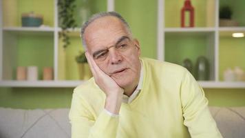 riflessivo infelice pensionato vecchio uomo a casa. il vecchio uomo è annoiato a casa, infelice e premuroso. video