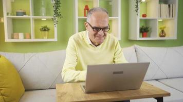 Old man in glasses using laptop at home, working, doing research. Happy relaxed old man is using laptop at home. Doing research, retired CEO, using social media. video