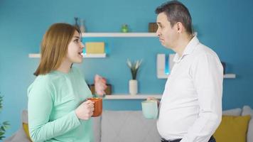 Father and daughter are drinking coffee and chatting. At home, father and adult teenage daughter drinking coffee and chatting together. video