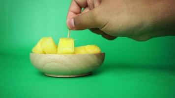 Taking slices of yellow watermelon in wooden plate with toothpick. yellow watermelon cuts in green background video