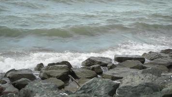 mar onda exitos a pedregoso costa. a surfar exitos a pedras em a costa e espirrando. video