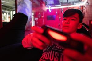 Teenager boy gamer play gamepad video game console in red gaming room. photo