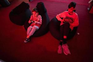 Two boys gamers play gamepad video game console in red gaming room. photo