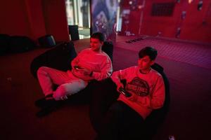 Father and son play gamepad video game console in red gaming room. Dad and kid gamers. photo