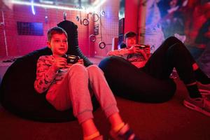 Two boys gamers play gamepad video game console in red gaming room. photo