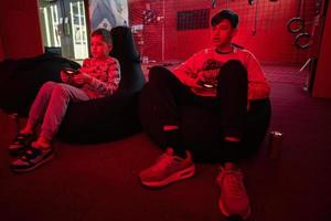 Two boys gamers play gamepad video game console in red gaming room. photo