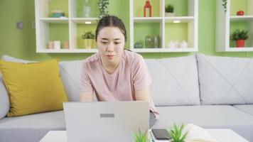 joven asiático mujer con ansiedad consiguiendo estresado a hogar. estresado asiático joven mujer con ansiedad trabajando desde hogar con ordenador portátil. video