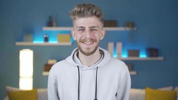 Happy positive young man looking at camera and crosses arms. Successful handsome smiling young man crossing his arms and confident in front of camera at home. video