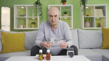 The grumpy, senile man using over-the-counter drugs. A senile old man taking medicine by heart. video