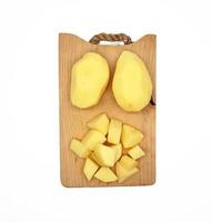 Diced peeled potatoes and whole peeled potatoes, on a wooden cutting board photo