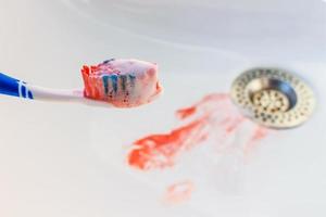 Blood on toothbrush on background of sink. photo