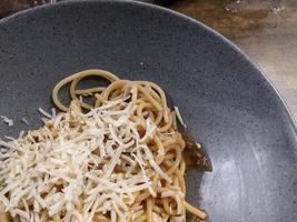 Spaghettis Bolognese with cheese cheddar topping on the grey bowl. The photo is suitable to use for food background, poster and food content.