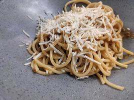 Spaghettis Bolognese with cheese cheddar topping on the grey bowl. The photo is suitable to use for food background, poster and food content.