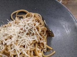 Spaghettis Bolognese with cheese cheddar topping on the grey bowl. The photo is suitable to use for food background, poster and food content.