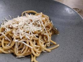 Spaghettis Bolognese with cheese cheddar topping on the grey bowl. The photo is suitable to use for food background, poster and food content.