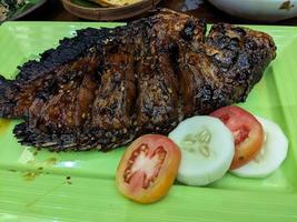 Traditional Fish Barbeque with sweet ketchup with cucumber and tomato. The photo is suitable to use for traditional food background, poster and food content.