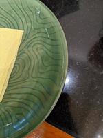 Empty green plate over the shiny table on the restaurant. The photo is suitable to use for restaurant background, menu poster and food content media.