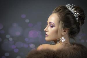 Beautiful model in profile with fashionable makeup in furs. Luxury winter girl on a gray background with bokeh. photo