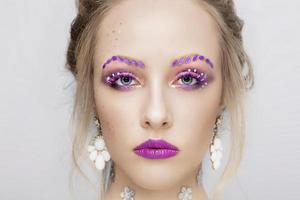 The face of a young girl. Model with purple make-up. Fancy eyebrows.Woman portrait close. photo