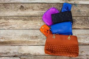 Colored handbags on wooden background. Top view. photo
