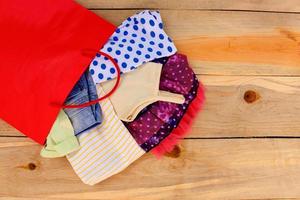 Women's clothing falls out of paper shopping bags on wooden background. photo