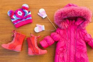 Children's winter clothes warm pink jacket, hat, mittens, boots. Top view. photo