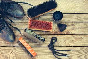 Shoes and care products for footwear on wooden background. Toned image. Top view. photo