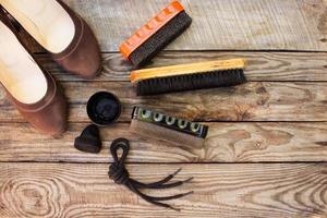 Shoes and care products for footwear on wooden background. Toned image. Top view. photo