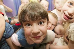 Funny face of a girl on a background of children. Child in kindergarten photo
