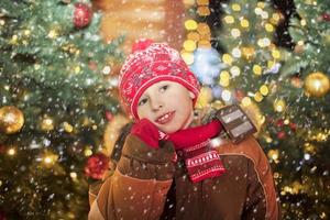 Baby on christmas background. A boy in a red hat on Christmas street. photo