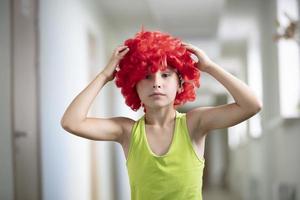 A child in a bright wig. Funny boy with red artificial hair. photo