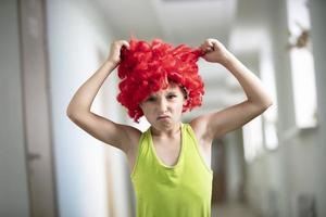 A child in a bright wig. Funny boy with red artificial hair. Do not like the hairstyle .. photo