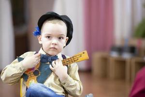 Russian boy with a balalaika. Funny preschooler with Russian folk musical instrument. photo